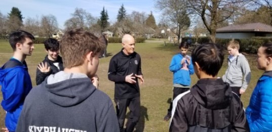 A referee speaking with young players outdoors