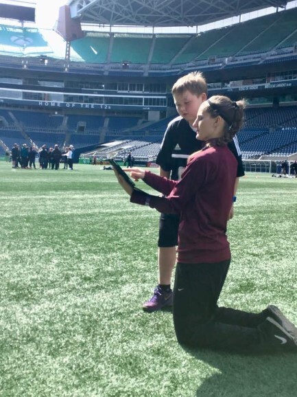 A mentor showing a young referee something on the field at a stadium