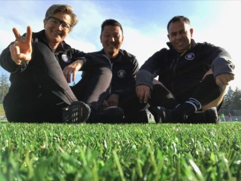 Three soccer referees sitting together on the grass